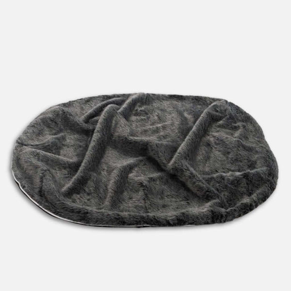 En mörkgrå, oval formad fuskpälsmatta med en mjuk, plyschig textur - som påminner om en grå vargs vandring - är utspridd på en vit bakgrund.