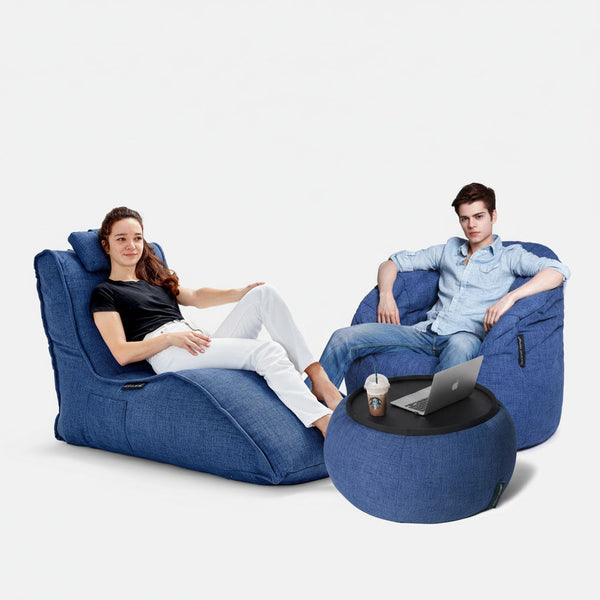 Två personer kopplar av i stora blå saccosäckar från Loft Package, med en matchande blå ottoman mellan sig. De skapar en mysig sittgrupp för streaming eller chatt mot en vit bakgrund.