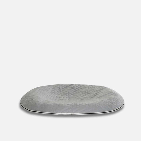 En stor, rund, grå quiltad golvdyna med en lätt indragen mitt, utformad som en vannavvisande hundeseng med ThermoQuilt-material, placerad på en vit bakgrund.