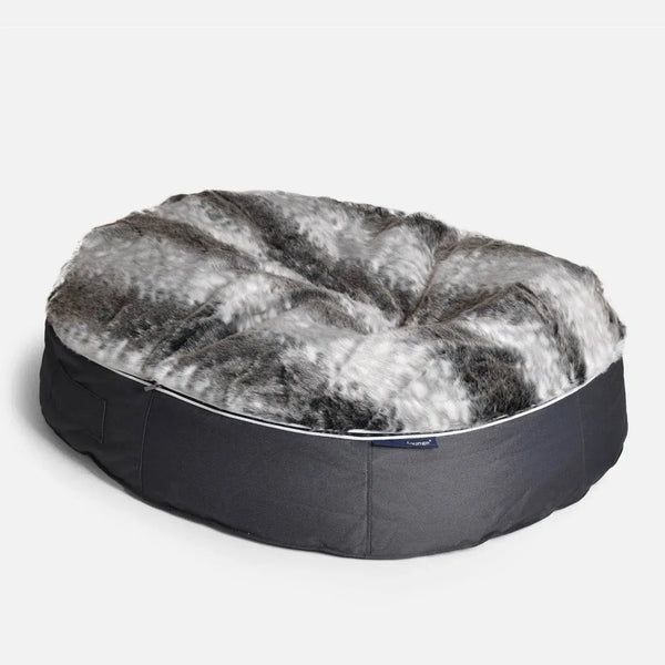 En rund, plyschig Ambient Lounge hundeseng med en topp i fuskpäls i nyanser av grått, svart och vitt och en bas i mörkgrått tyg. Den här sängen ser mjuk och bekväm ut - perfekt för katter eller till och med stora hundar som vill ha det mysigt.