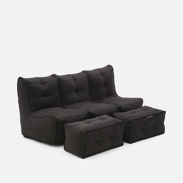 En modern, mörkgrå Mod 3 Movie Couch tresitssoffa med tuftad design, tillsammans med två matchande rektangulära ottomaner, mot en vit bakgrund.