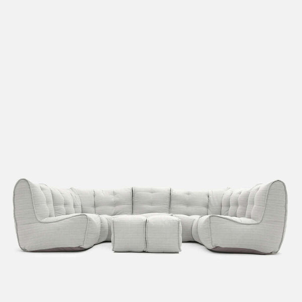 En modern, ljusgrå Ambient Lounge sektionssoffa med djupa kuddar och två matchande fyrkantiga ottomaner, alla placerade i en L-form mot en vit bakgrund, perfekt för att skapa en mysig loungesoffa.