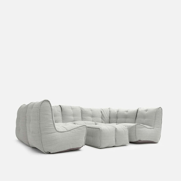 En modern, ljusgrå Ambient Lounge sektionssoffa med djupa kuddar, tuftad klädsel och låg profil, mot en vit bakgrund.
