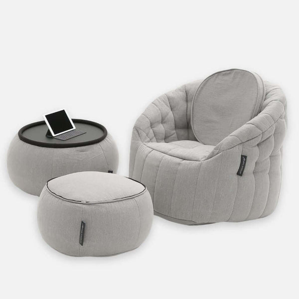 Ett modernt, ljusgrått fåtöljset från Contempo Indoor Package har mjuka, rundade kanter och inkluderar en matchande ottoman samt ett litet bord med en svart bricka som rymmer en surfplatta - allt tillverkat i mjukt, quiltat tyg för en elegant modern möblering.