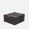 En fyrkantig, mörkgrå, tuftad Twin Ottoman golvdyna från Ambient Lounge, med en tygetikett på framsidan, ligger mot en vit bakgrund - perfekt för fans av moderna möbler.